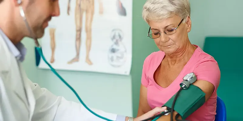 Starsza kobieta ma badane ciśnienie krwi przez lekarza w Domu Seniora Dąbrówka w Baninie